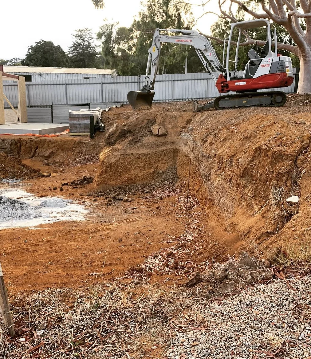 Valley excavator above an exposed earth cut on a residential site