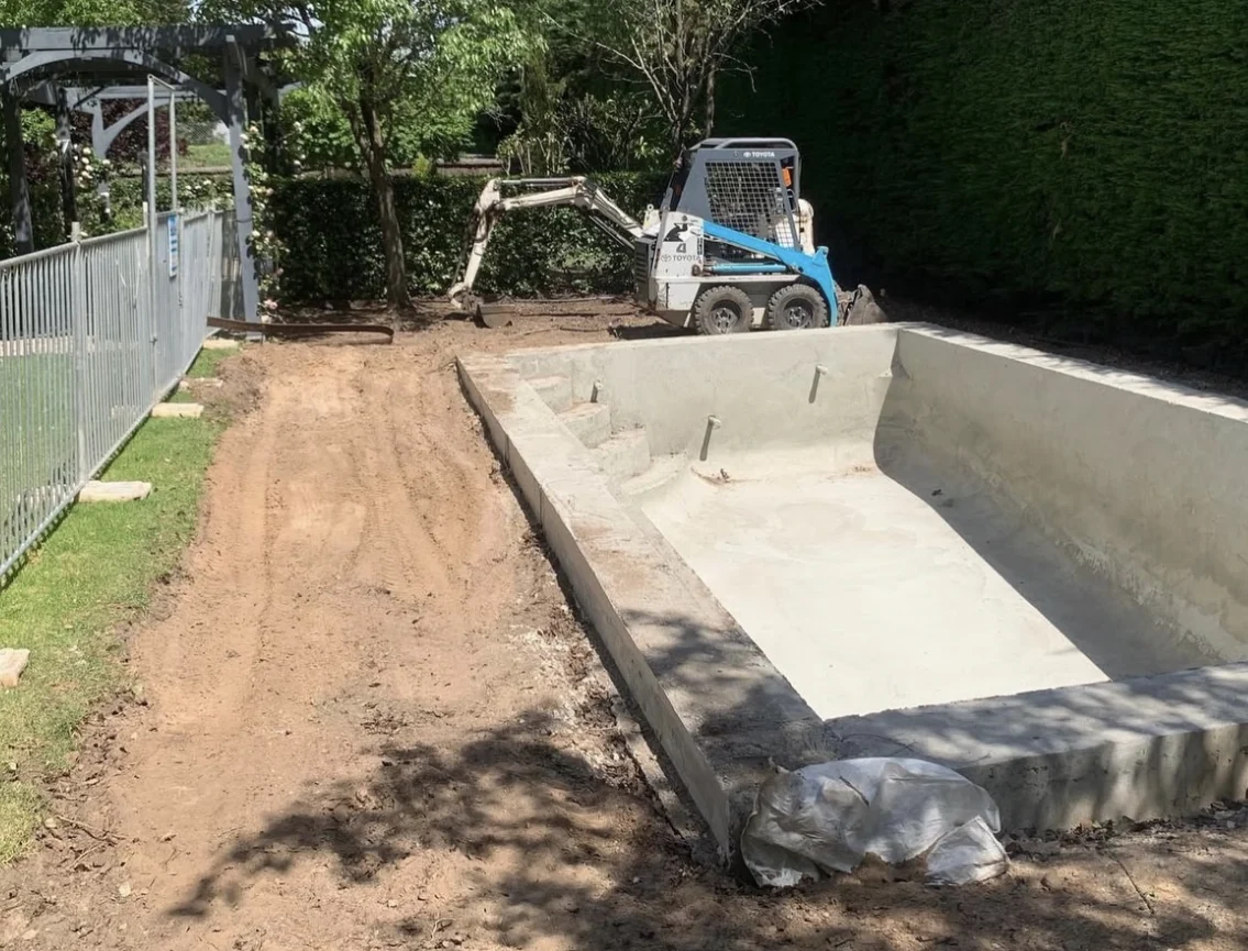 Pool shell with excavated surrounds and compact machinery during construction
