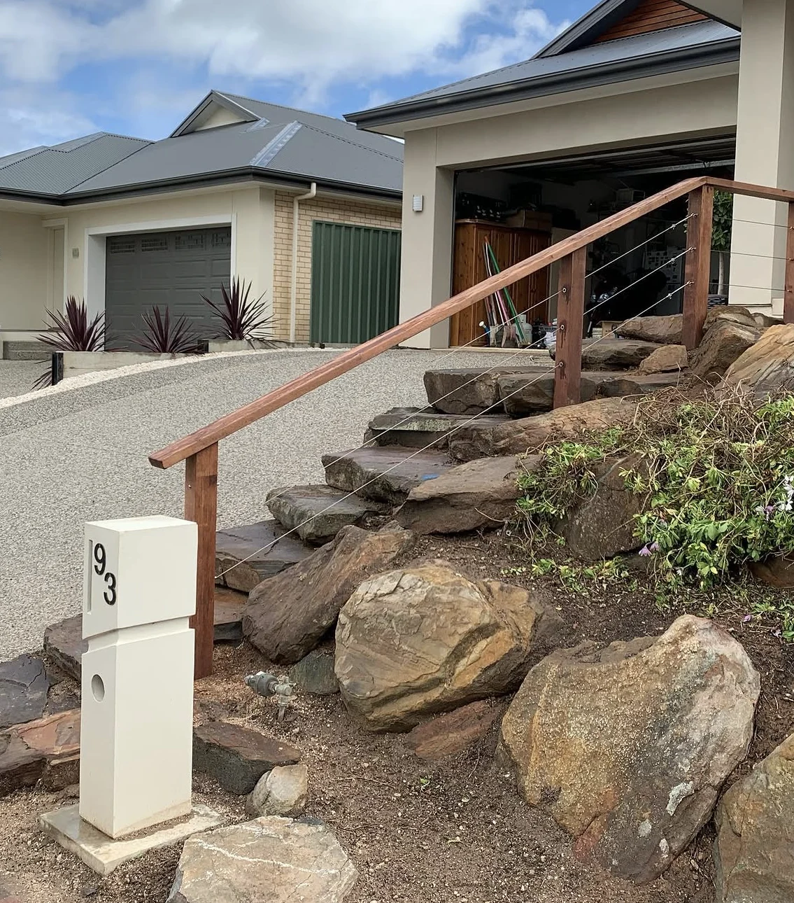 Natural moss rock steps with a timber handrail connecting garden levels